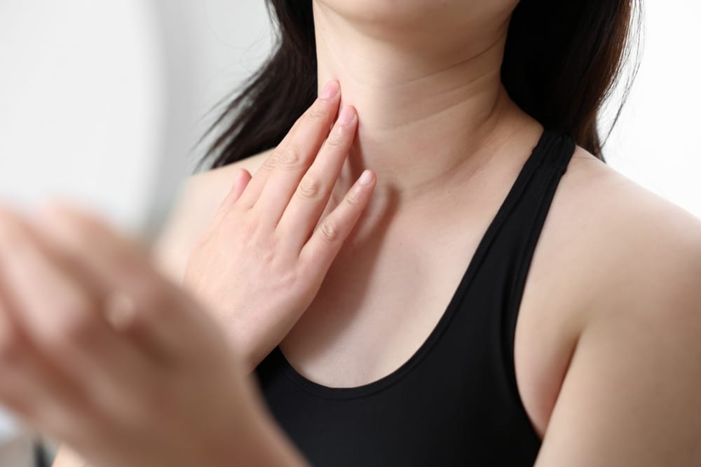 Close-up of a woman touching her neck, symbolizing non-surgical neck rejuvenation.