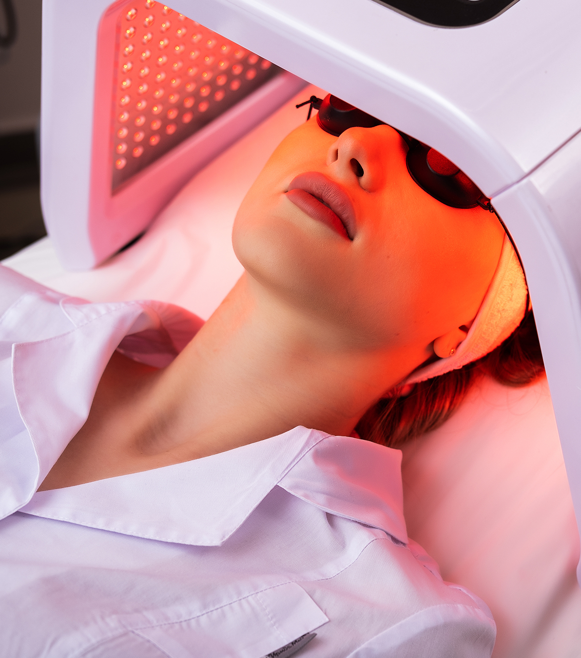 Woman receiving red light therapy facial to boost collagen and reduce fine lines for glowing skin.