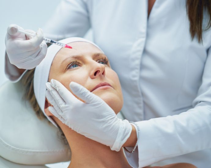 Female patient receiving precise facial injection from a trained medical professional in a clinical setting for filler correction