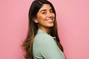 Smiling woman with thick nasal skin and smooth complexion, showcasing natural rhinoplasty outcome for dense skin