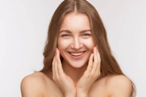 Smiling woman with glowing skin and natural appearance, representing the 2025 trend of subtle facial enhancements at The Naderi Center.