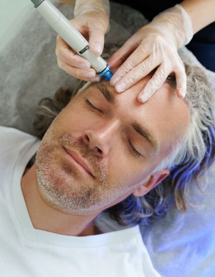 Man with closed eyes receiving aesthetic procedure, showing specialized skincare treatments available for men.