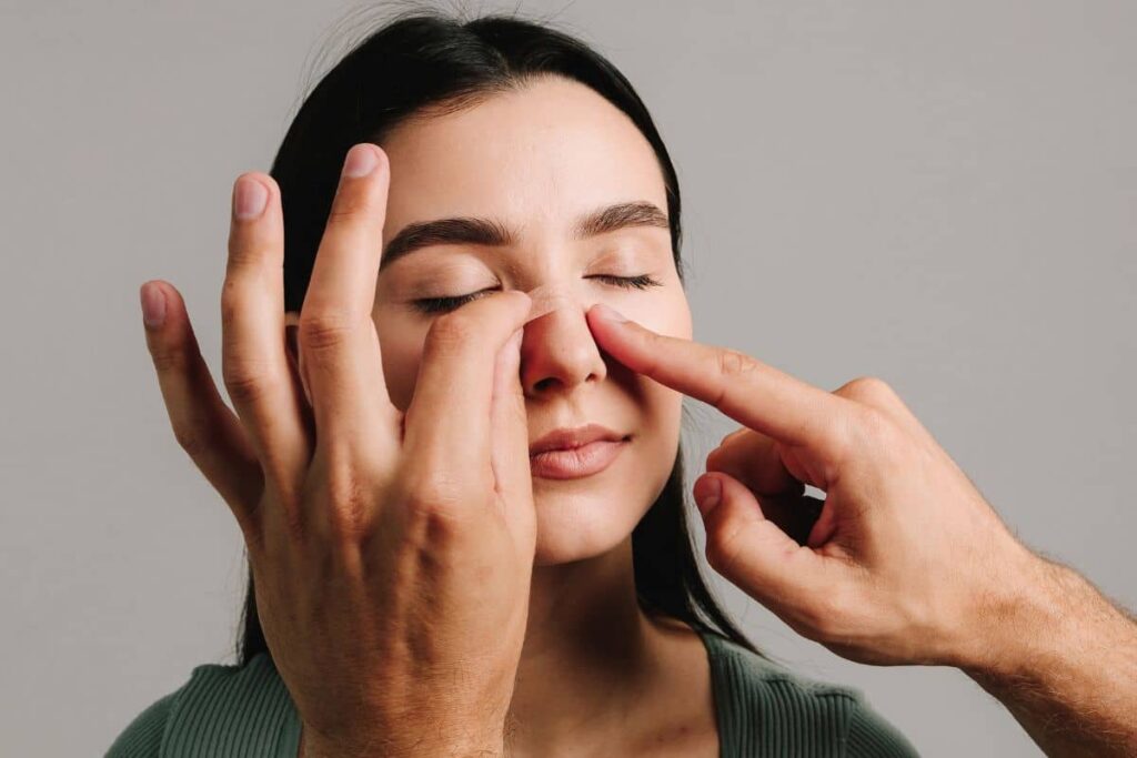 Applying tape to patient’s nose as part of post-rhinoplasty recovery