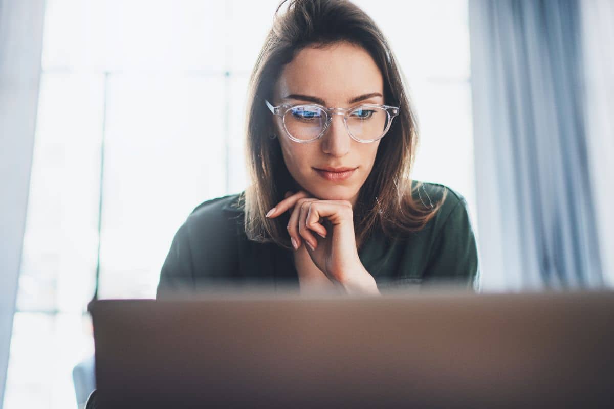 Young woman looking at laptop screen while researching rhinoplasty surgery options and international clinic safety.