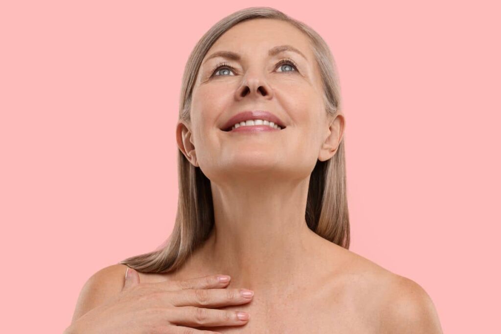 Smiling older woman touching neck, representing various neck rejuvenation treatment options and associated costs.
