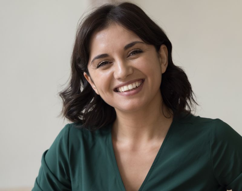 Confident Persian woman smiling, showcasing natural-looking results of non-surgical rhinoplasty using dermal fillers.