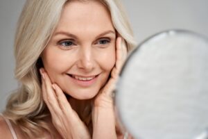 Smiling older woman with natural facial features showing rejuvenation benefits after rhinoplasty in later age.