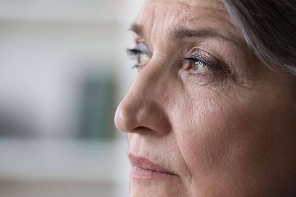 Close-up side view of older woman’s face showing healthy skin and structure, assessing rhinoplasty candidacy.
