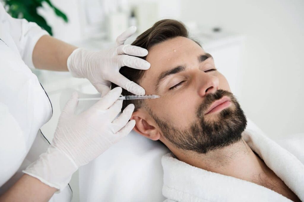 Man receiving Botox injection near temple, highlighting personalized dosage approach based on facial muscle strength and goals.