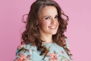 Woman with youthful, full face and styled curls, reflecting facial rejuvenation after Ozempic-related weight loss.