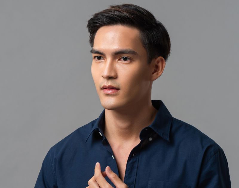 Asian man with defined nasal features representing rhinoplasty results addressing low bridge and cartilage support.