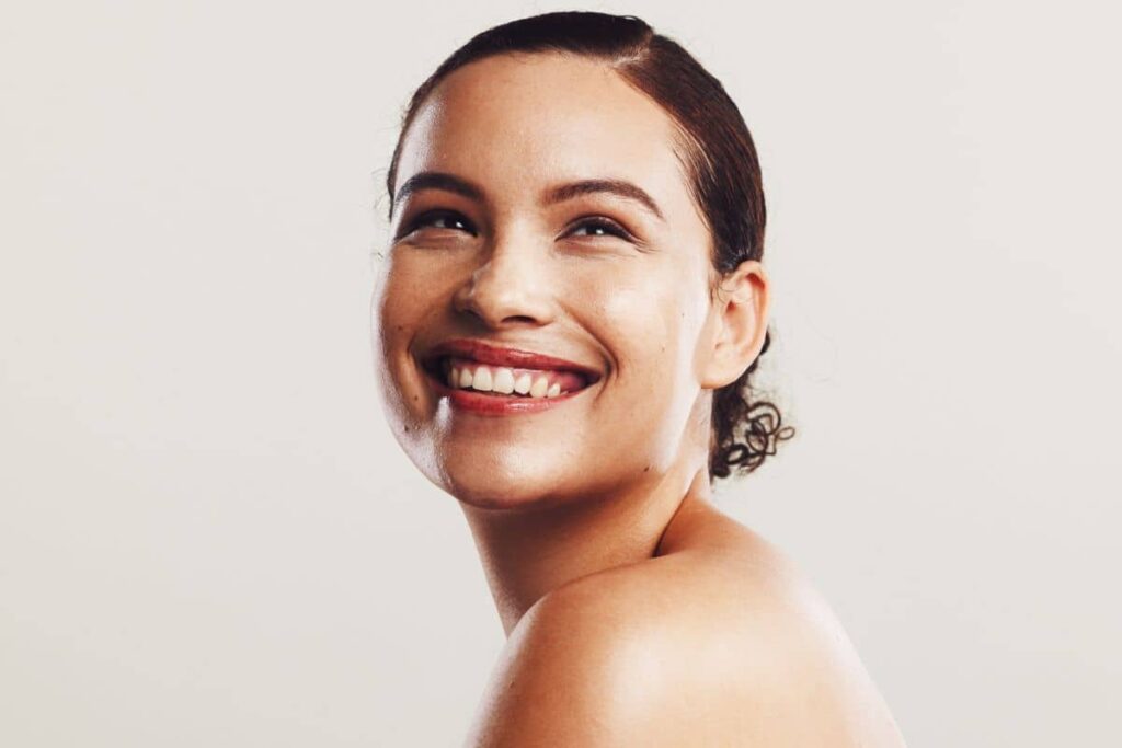 Woman with glowing, even-toned skin smiling after successful hyperpigmentation treatment for ethnic skin types.