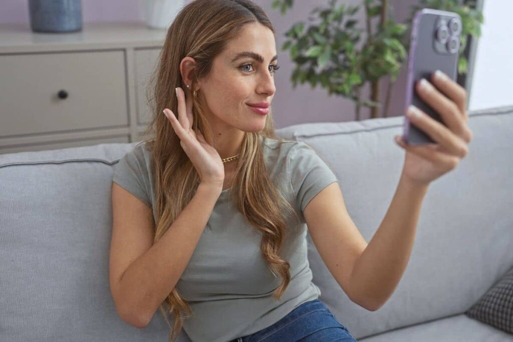 Woman taking a selfie, showcasing the contrast between temporary filters and real, long-lasting results of personalized facelifts.