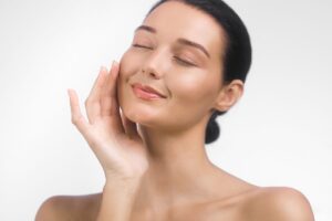 Woman with glowing skin smiling gently, representing facial harmony and balanced aesthetic enhancement approach.