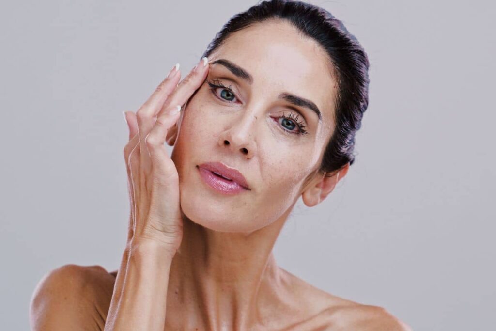 Woman touching her face, showing concern for facial volume loss and skin laxity from GLP-1 medication use.