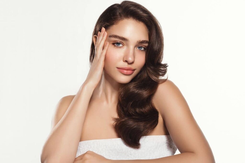 Clear-skinned woman touching face, representing PRF injections for facial rejuvenation and natural hair growth support