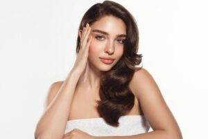 Clear-skinned woman touching face, representing PRF injections for facial rejuvenation and natural hair growth support