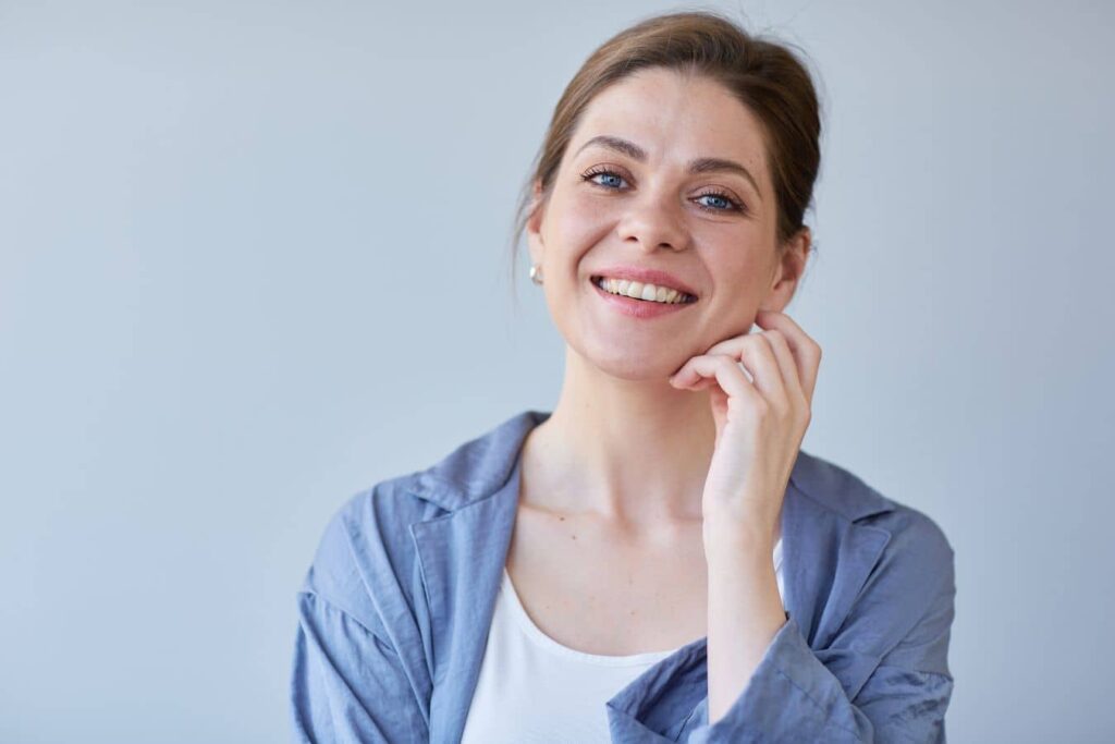 Woman with clear skin smiling and touching face, illustrating smooth results after botulinum toxin cosmetic treatment