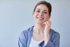 Woman with clear skin smiling and touching face, illustrating smooth results after botulinum toxin cosmetic treatment