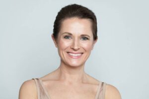 Smiling middle-aged woman with smooth, firm skin illustrating natural results of deep plane facelift.