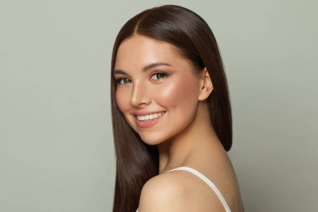 Woman with smooth skin and natural makeup smiling, showcasing natural enhancement and undetectable aesthetic results