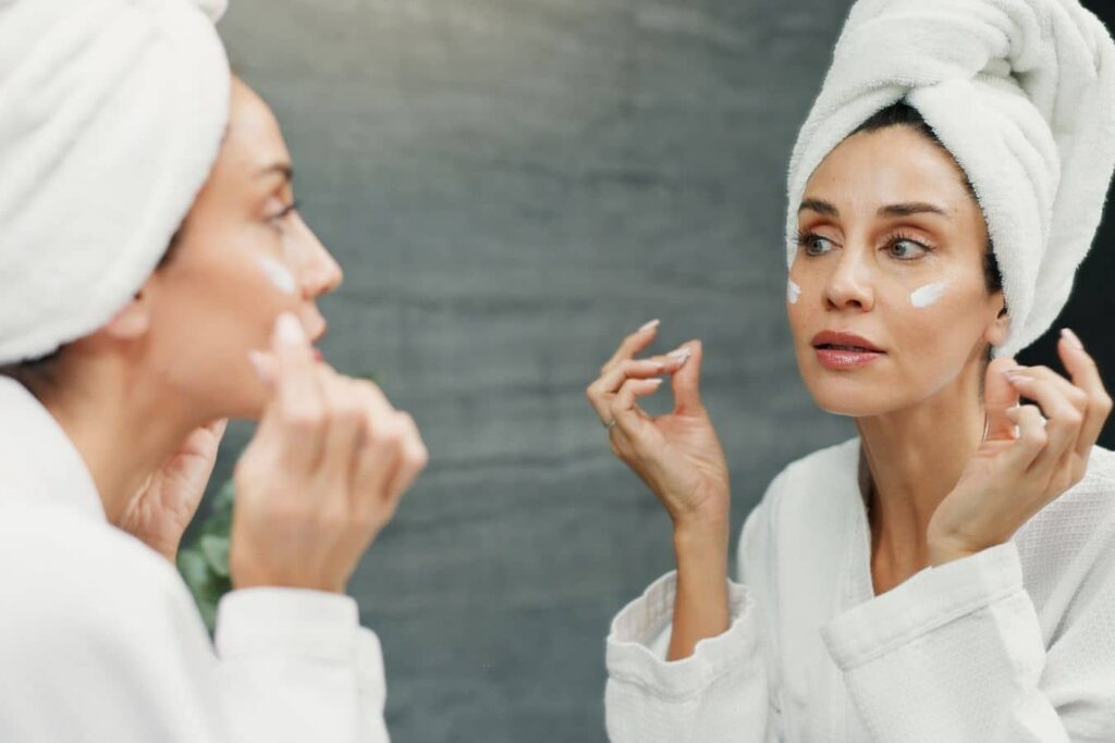 Woman applying skincare after laser resurfacing treatment to maintain healthy, rejuvenated skin results.