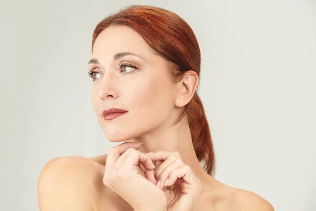 Red-haired woman with a defined jawline illustrating the importance of proper timing and realistic expectations for facelift surgery.