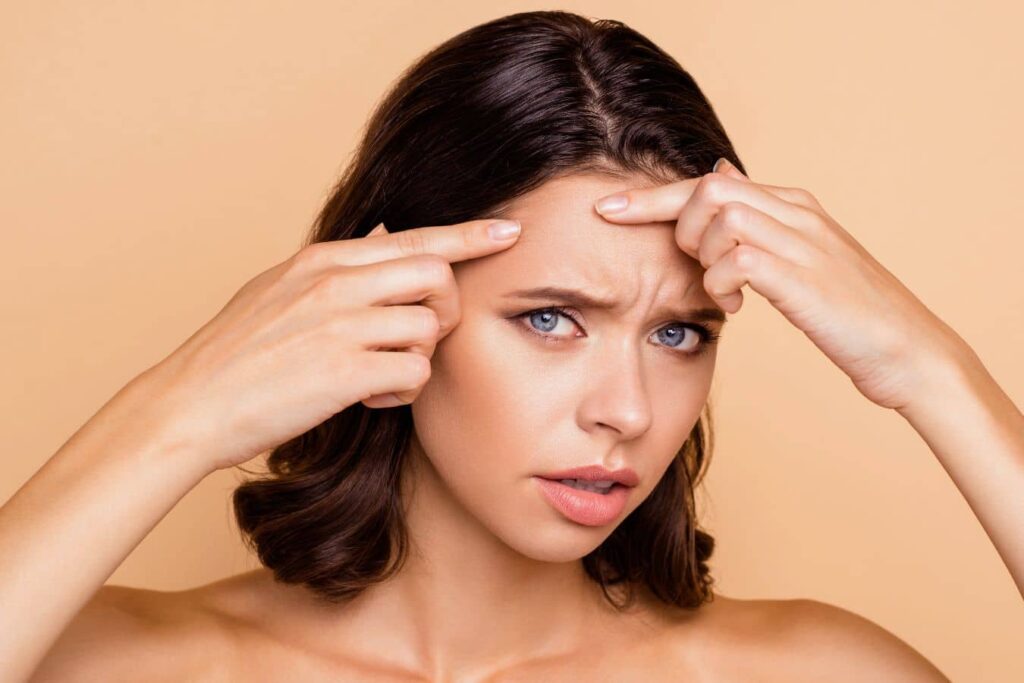 Woman pointing to glabella frown lines, highlighting brow area concerns for filler injection treatment