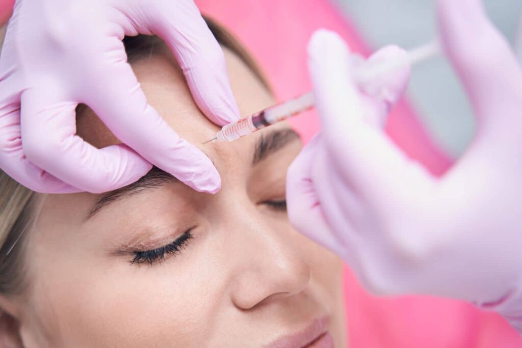 Specialist performing glabella filler injection between the brows for frown line treatment