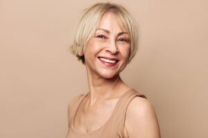 Confident mature woman smiling with refreshed appearance, illustrating natural results achieved through deep plane facelift techniques.