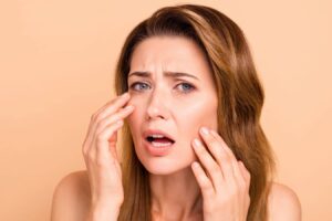 Concerned woman touching her face, illustrating unnatural facelift results and common surgical mistakes discussed in facelift surgery.