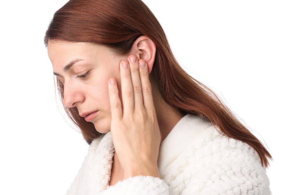 Woman touching the area near her ear, highlighting hairline and ear distortion risks after facelift surgery.