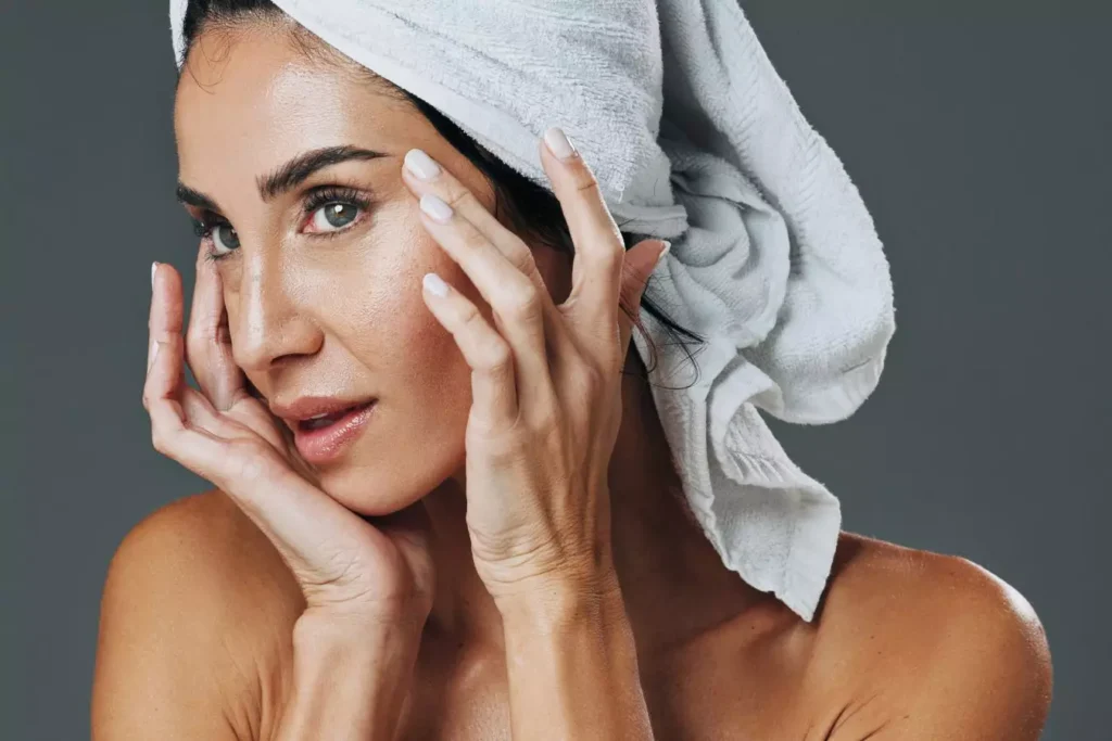 Woman touching facial skin during a skincare routine.